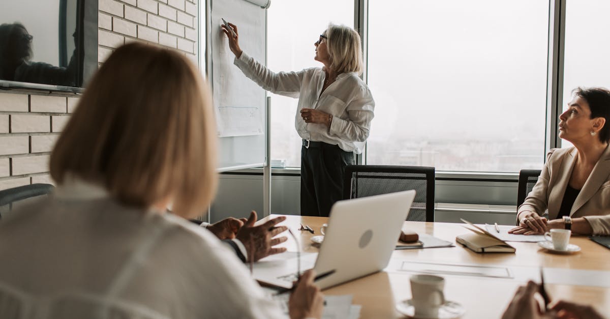 Executive presenting strategy on whiteboard during office meeting.